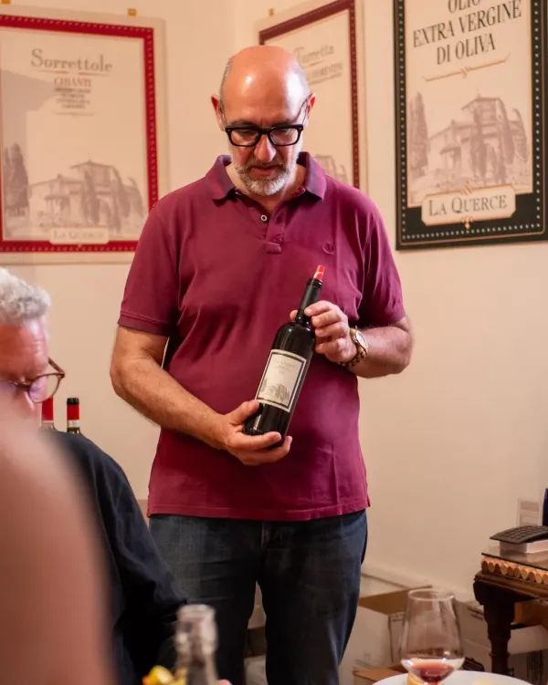 Il produttore presenta una bottiglia agli ospiti durante la degustazione in cantina